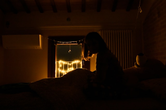 The picture shows a woman awake in the middle of the night because of college enrollment worries.