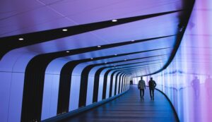The picture shows two people walking into a futuristic looking tunnel to represent predicting future priorities in higher ed.