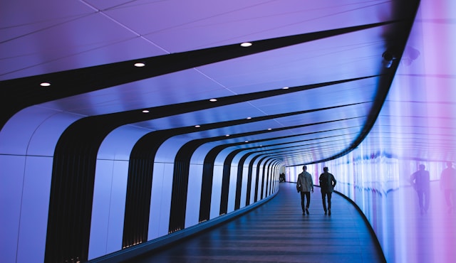 The picture shows two people walking into a futuristic looking tunnel to represent predicting future priorities in higher ed.